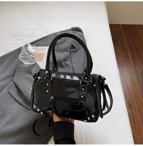 Détail du sac en cuir verni noir brillant avec des rivets argentés et de longs glands