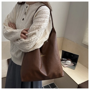 Detailed side view of a brown faux leather tote bag with gold lettering for daily use