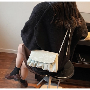 Detail of light green pleated leather bag with marble texture flap and chain strap