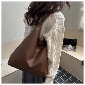 Detailed side view of large brown vintage tote bag in oil wax leather finish with gold text