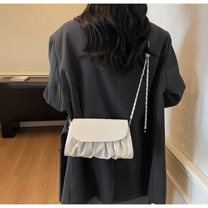 Rear view of a pleated cream crossbody bag showing realistic proportions on a model