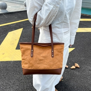 Détail du sac cabas en daim avec surpiqûres en losange et anse en cuir marron