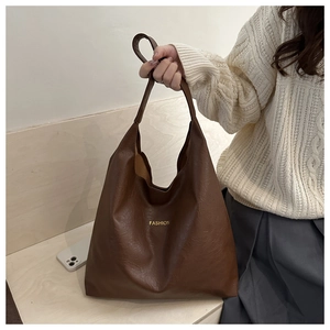 Close-up of vintage brown oil wax leather tote bag with gold fashion lettering logo