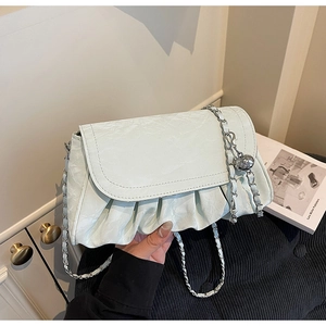 Detail of mint green pleated crossbody bag with silver chain and metal ball charm