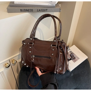Vue détaillée du sac Boston marron foncé brillant avec rivets et longs glands en cuir