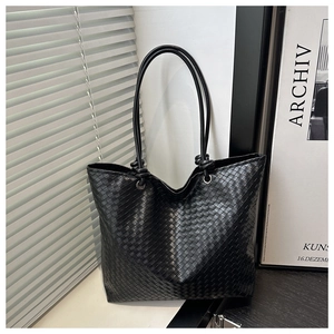 Detail of black woven tote bag with Intrecciato craft and unique knotted shoulder strap