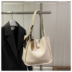 Detail of a large cream tote bag with an elegant floral scarf on the shoulder strap
