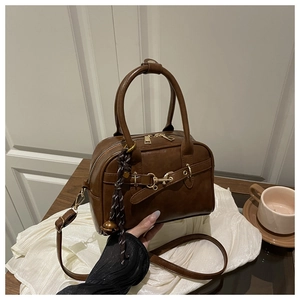 Détails du sac à main vintage marron avec pompon décoratif et boucle dorée élégante