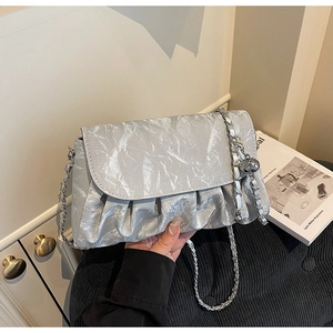 Detail of silver pleated faux leather crossbody bag with chain strap and metal bead