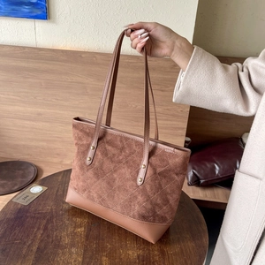 Détail d'un sac cabas en daim marron avec surpiqûres en losanges et rivets en métal doré