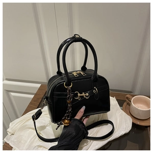 Détail d'un sac à main rétro noir avec mors doré et pendentif en corde tressée