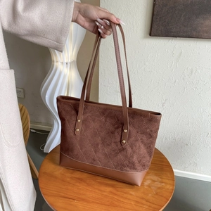 Détail du grand sac fourre-tout en daim marron avec matelassage et rivets dorés