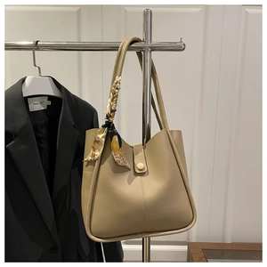 Detail of beige faux leather tote bag featuring elegant silk scarf and magnetic closure