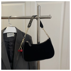 Detail of hobo bag with gold chain strap and decorative red cherry pendant
