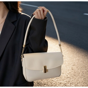 Minimalist beige shoulder bag with gold metal buckle shown on a female model side profile
