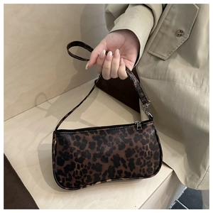 Detail der Baguette-Tasche mit Leopardenmuster und Goldkette am beigefarbener Trenchcoat