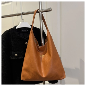 Close-up of caramel brown hobo bag with pebbled leather texture and gold FASHION lettering