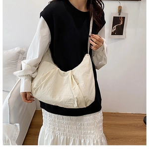 Detail view of large off-white pleated shoulder bag in lightweight nylon for daily commute