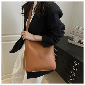 Detail view of large caramel brown faux leather bucket bag with matte finish on shoulder