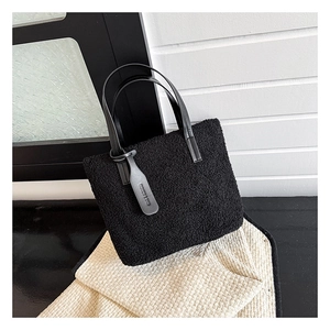 Close-up of black plush bucket bag featuring leather handles and fashion logo tag