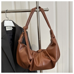 Detailed view of the brown lychee pattern leather bag with elegant knot strap detail