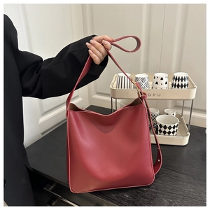 Close-up of red minimalist bucket bag featuring adjustable gold buckle on the strap