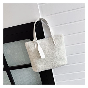 Detail of white plush bucket bag showing soft faux shearling texture and branded leather tag