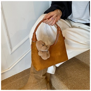 Detailed texture of brown suede hobo bag with a cute plush bear charm on zipper