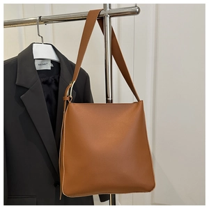 Close-up of brown leather crossbody bag with golden hardware and wide shoulder strap