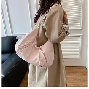 Close-up of pink nylon crescent bag with metal zipper pocket details and crinkled texture