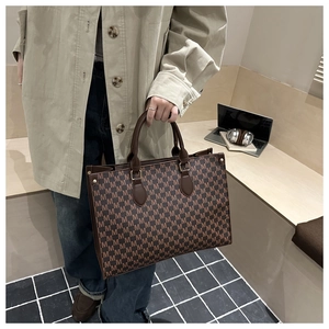 Detail of vintage patterned tote bag with M-letter monogram and leather handle