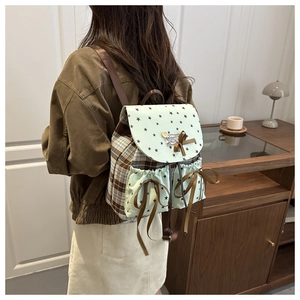 Detail of plaid school backpack with mint green star print and brown ribbon bows