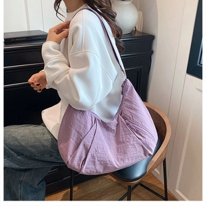 Lifestyle shot of large purple crescent shoulder bag with wide strap on a model