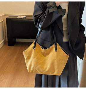 Detail of yellow quilted suede tote bag with golden lock and black shoulder straps