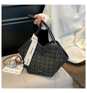 Detail of tweed tote bag featuring V-cut design, black gold textures and branded strap
