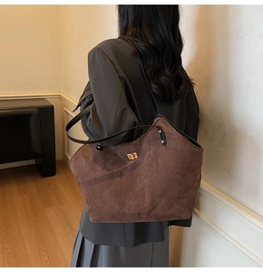 Detail of dark brown suede tote bag with quilted diamond pattern and gold rotary lock