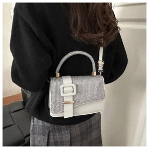 Silver glitter and white leather crossbody bag worn by a model in a casual indoor setting