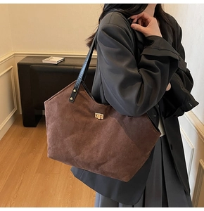 Detailed close-up of dark coffee quilted suede tote bag with golden turn-lock clasp