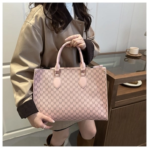 Pink tote bag detail with vintage 'M' print and sturdy double handles held by model