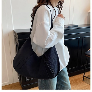 Side view of a large black crescent nylon tote bag shown on model for daily commuting