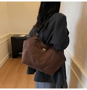 Brown suede tote bag with diamond quilted stitching and gold clasp shown on shoulder