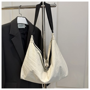 Detail of white wrinkled nylon dumpling bag with black wide strap and metal zipper