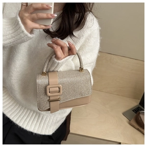 Details einer eleganten champagnergoldenen Handtasche mit Glitzertextur und Rundgriff