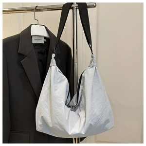 Detail of light blue pleated nylon tote bag with wide black shoulder strap and metal zippers