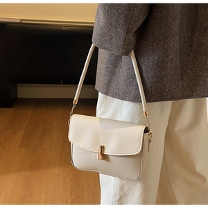 Detail of cream white shoulder bag featuring gold metal buckle and chain strap