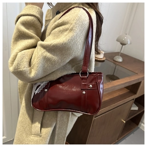 Detail of burgundy Boston bag with white lace trim and silver studs in a lifestyle setting