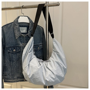 Gros plan d'un sac demi-lune bleu clair avec bandoulière noire et texture plissée