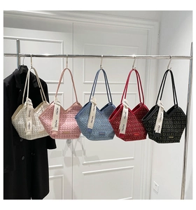 Close-up of five colorful textured tote bags with decorative ribbons on hangers