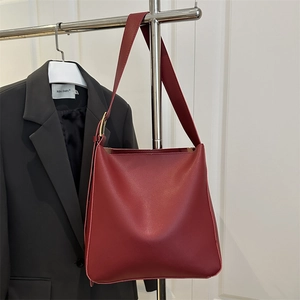 Minimalist deep red bucket tote bag with wide shoulder strap and gold metal hardware buckle