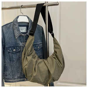 Détail du sac croissant plissé vert olive avec large bandoulière noire sur cintre